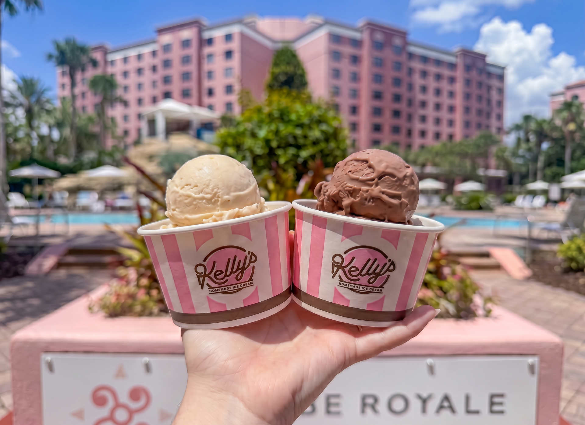 a hand holding two cups of ice cream
