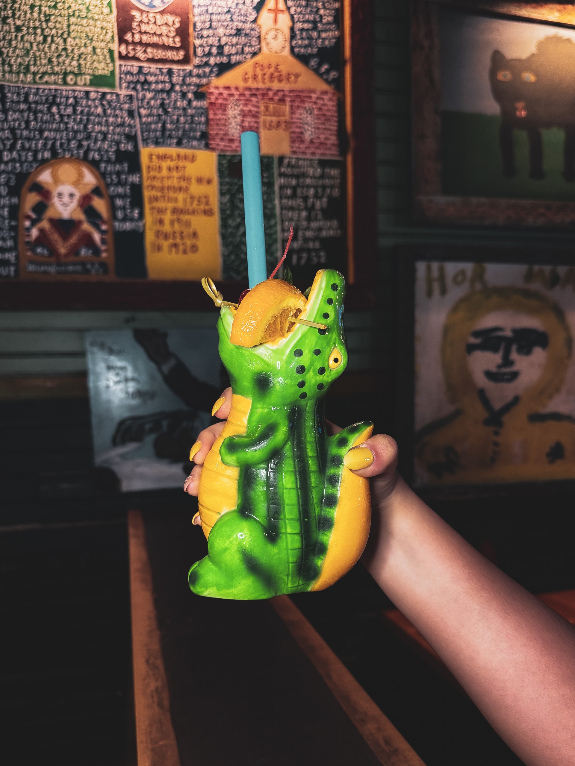 a hand holding a plastic alligator with a straw