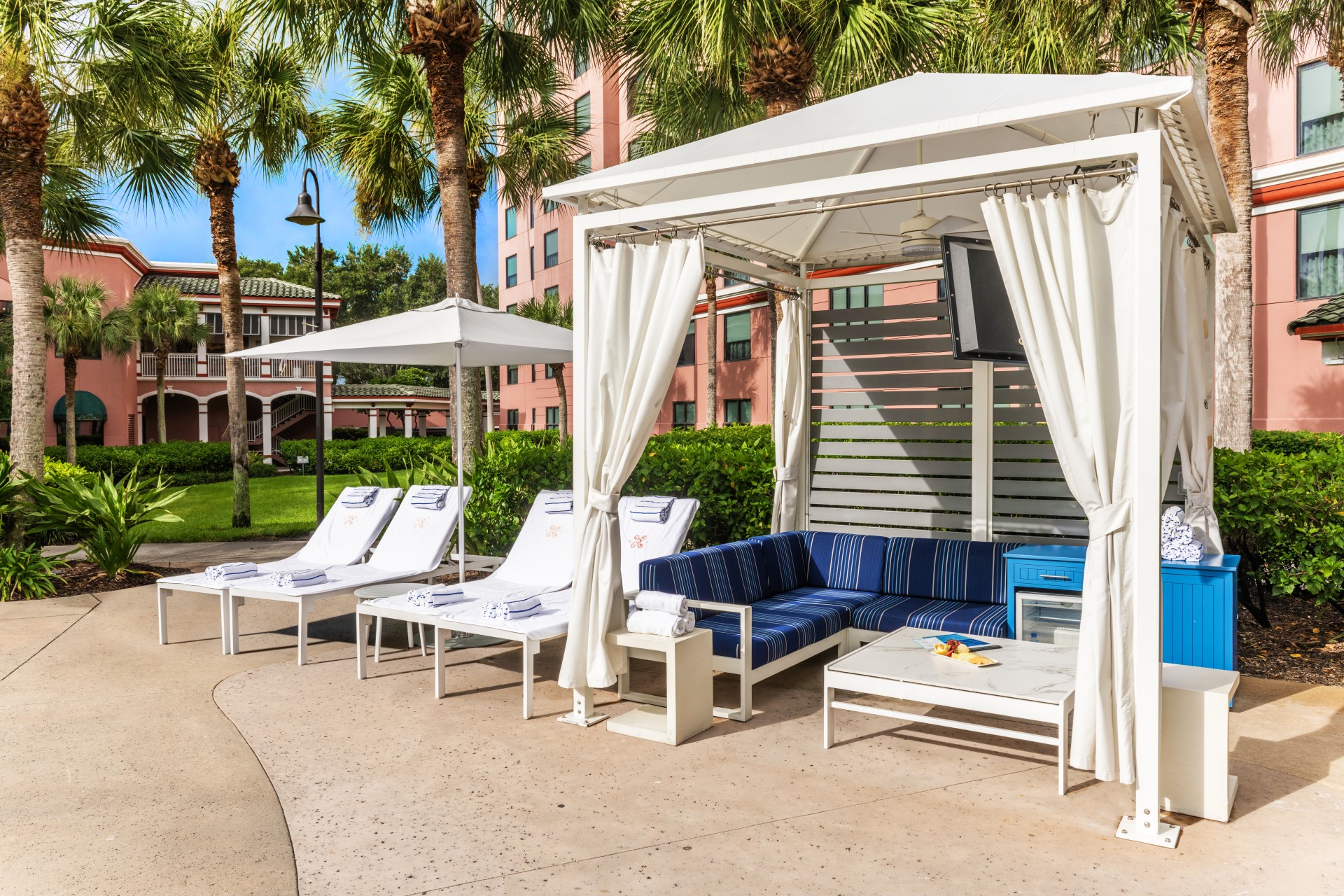 a white canopy with blue and white lounge chairs and umbrellas