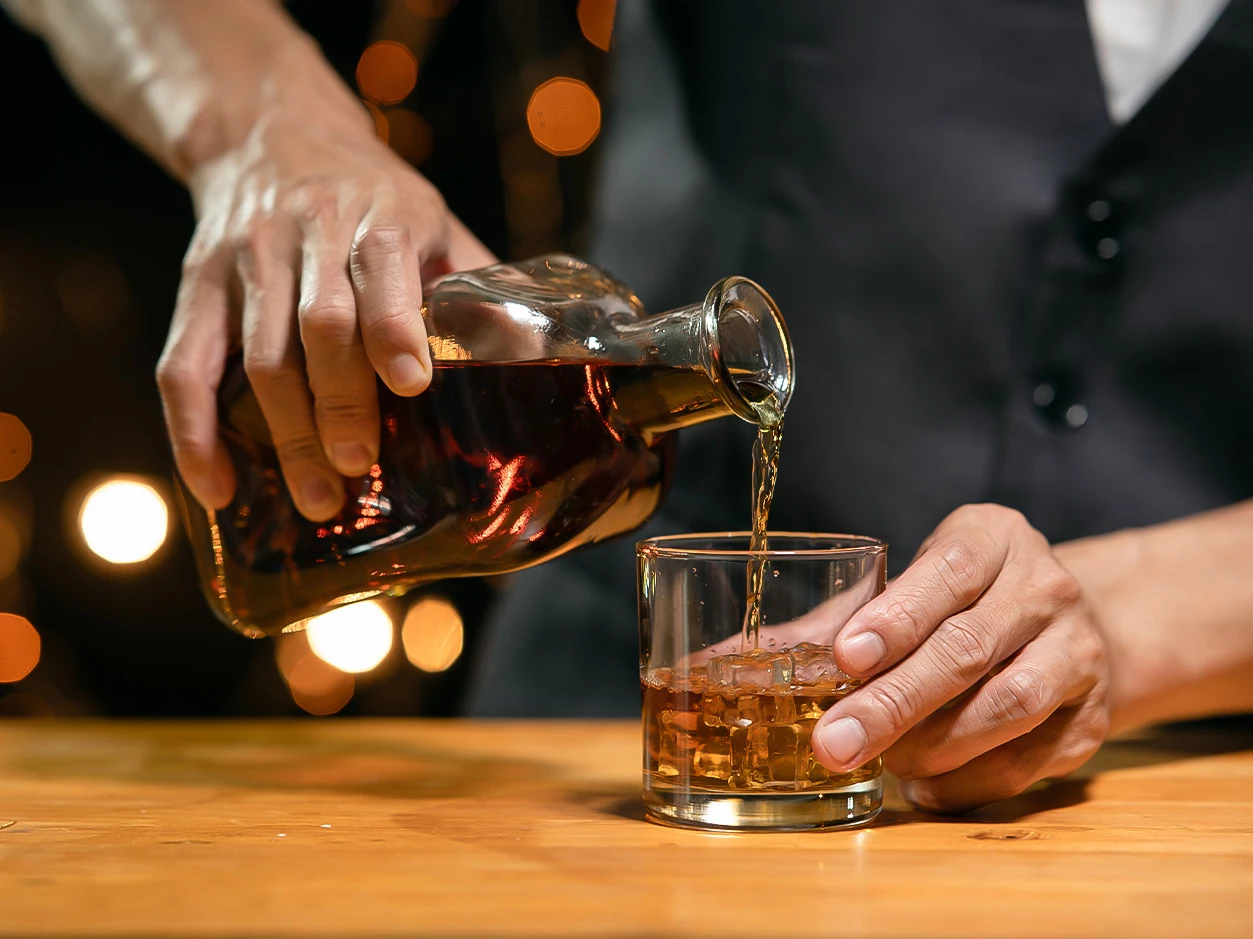 a person pouring a drink into a glass