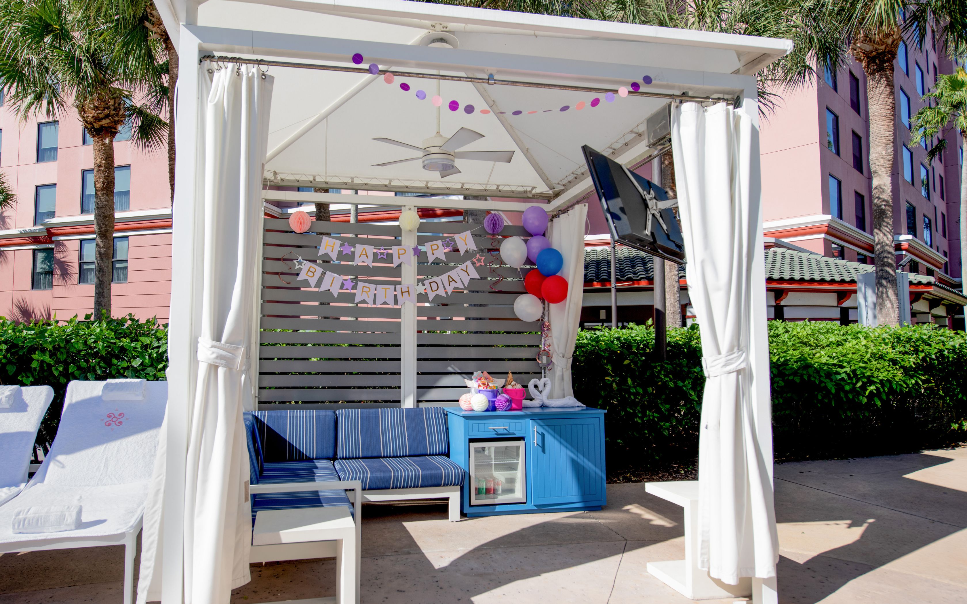 a white tent with blue couch and balloons
