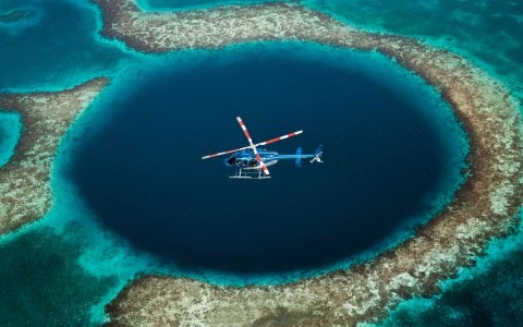 a helicopter flying over a planet with Great Blue Hole in the background