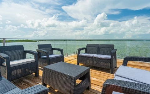 a deck with chairs and a body of water in the background