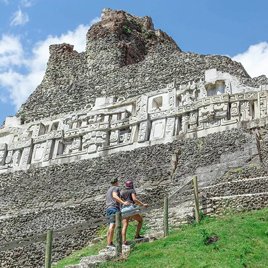 a couple of people posing in front of a large rock structure