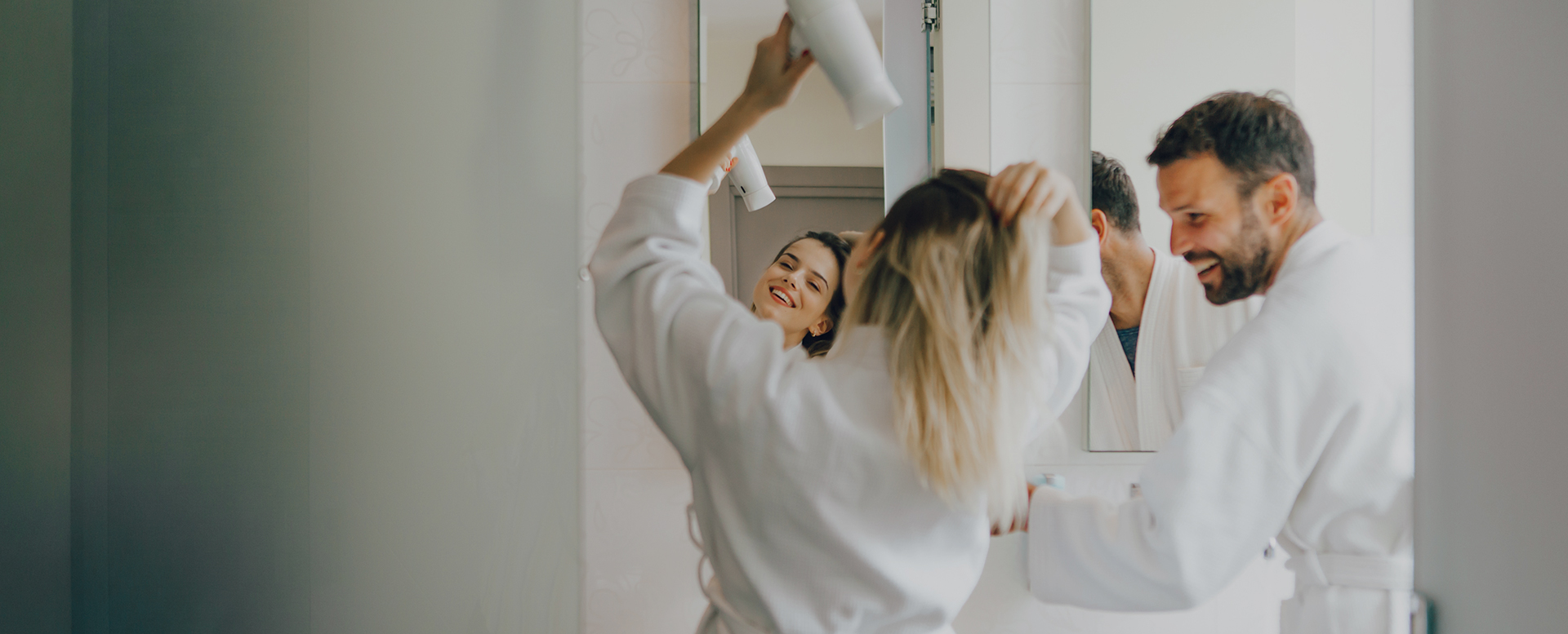 a woman in a white robe holding a hair dryer