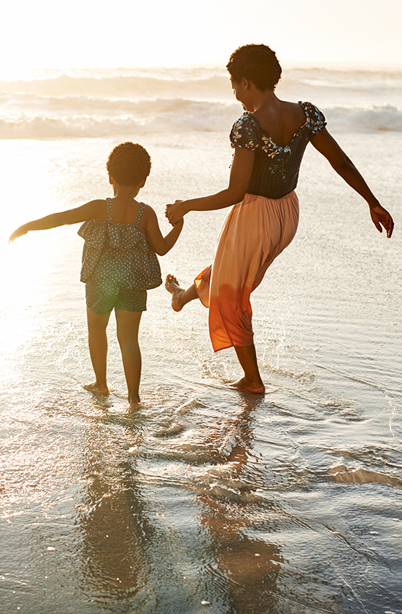 a woman and child walking on the beach