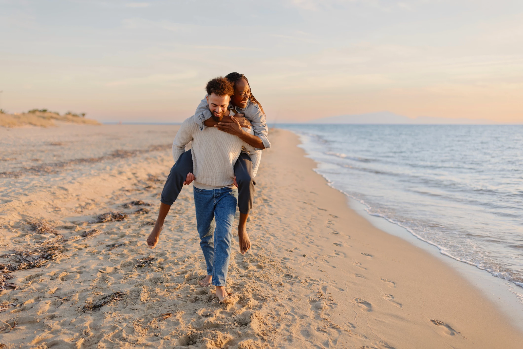 a man carrying a woman on his back on a beach