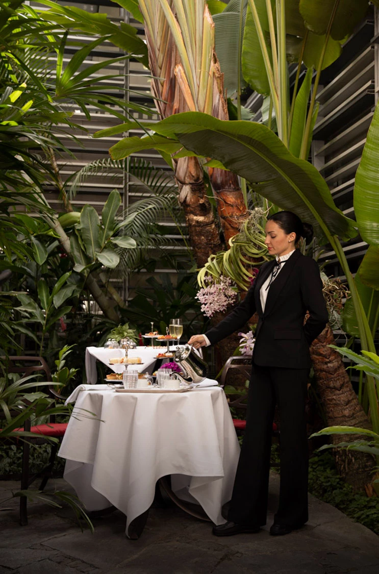 a woman in a suit pouring liquid into cups
