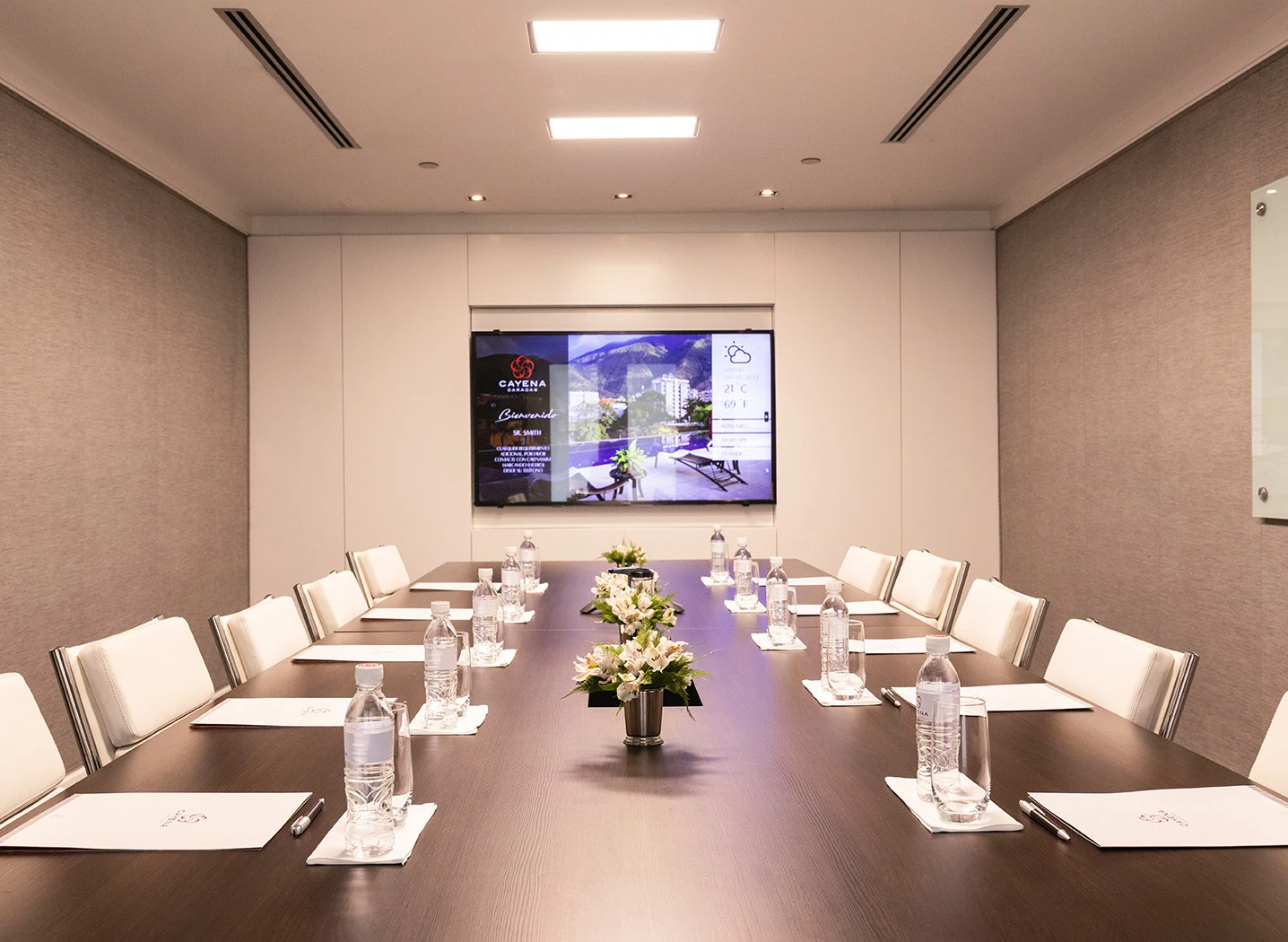 a conference room with a table and chairs in front of a large screen