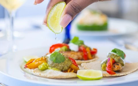 a person squeezing a lime on a plate of food