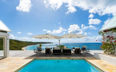 a pool with chairs and a beach in the background