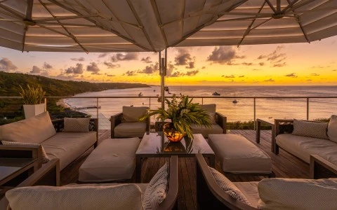 a deck with chairs and a table with a view of the ocean