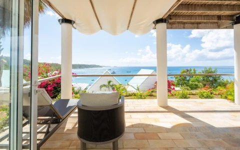 a patio with chairs and a view of the ocean