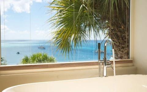 a sink with a view of the ocean and boats in the background