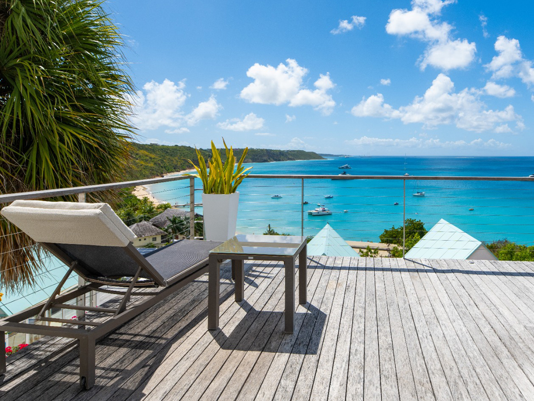 a deck with a chair and table overlooking a body of water