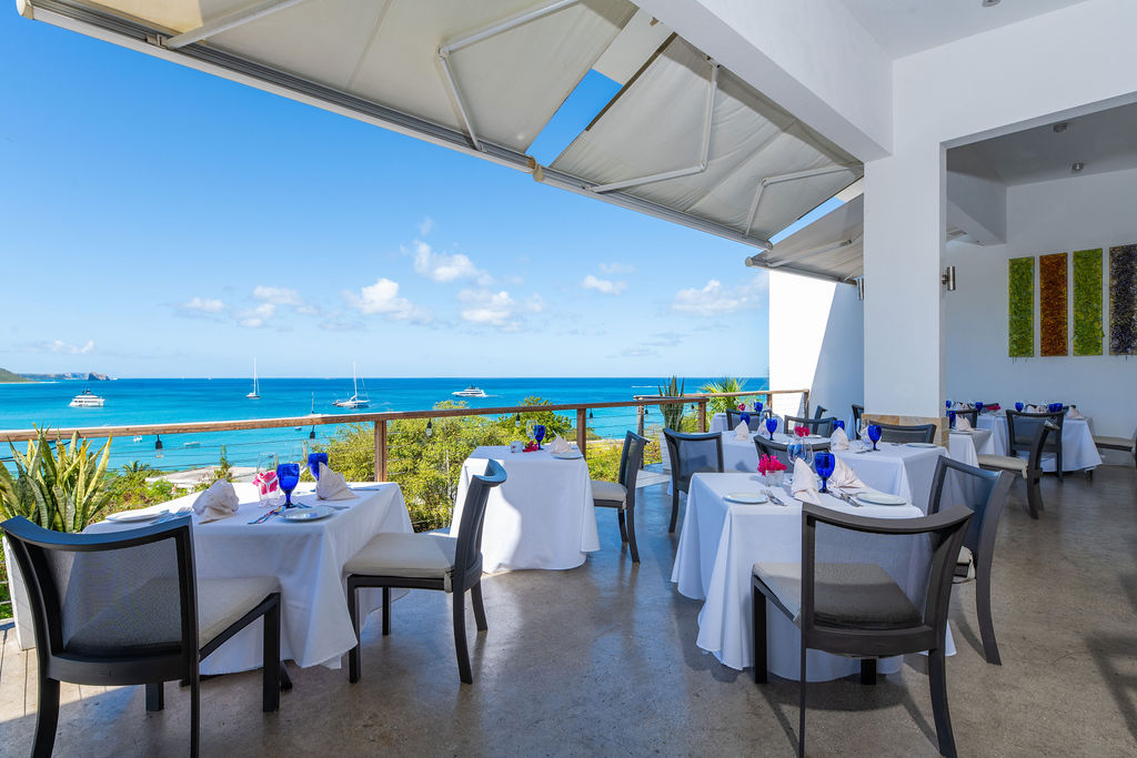 a restaurant with tables and chairs on a patio overlooking the ocean