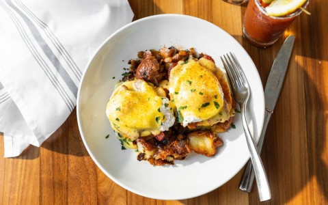 Plate of Peppered Bacon Benedict with breakfast potatoes
