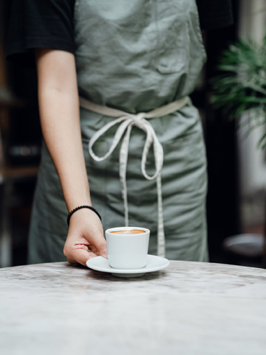 barista placing down a cup and saucer of coffee