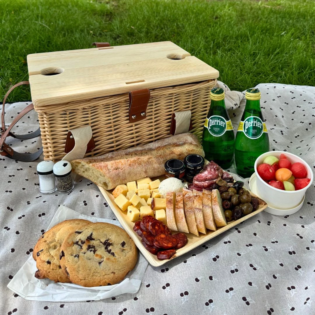 a picnic basket with food and drinks on a blanket