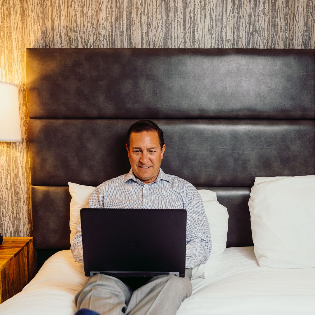 a man sitting on a bed using a laptop