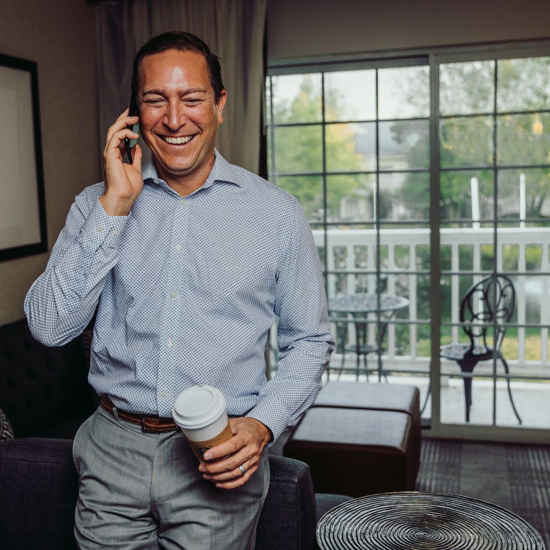 a man holding a coffee and talking on a cell phone