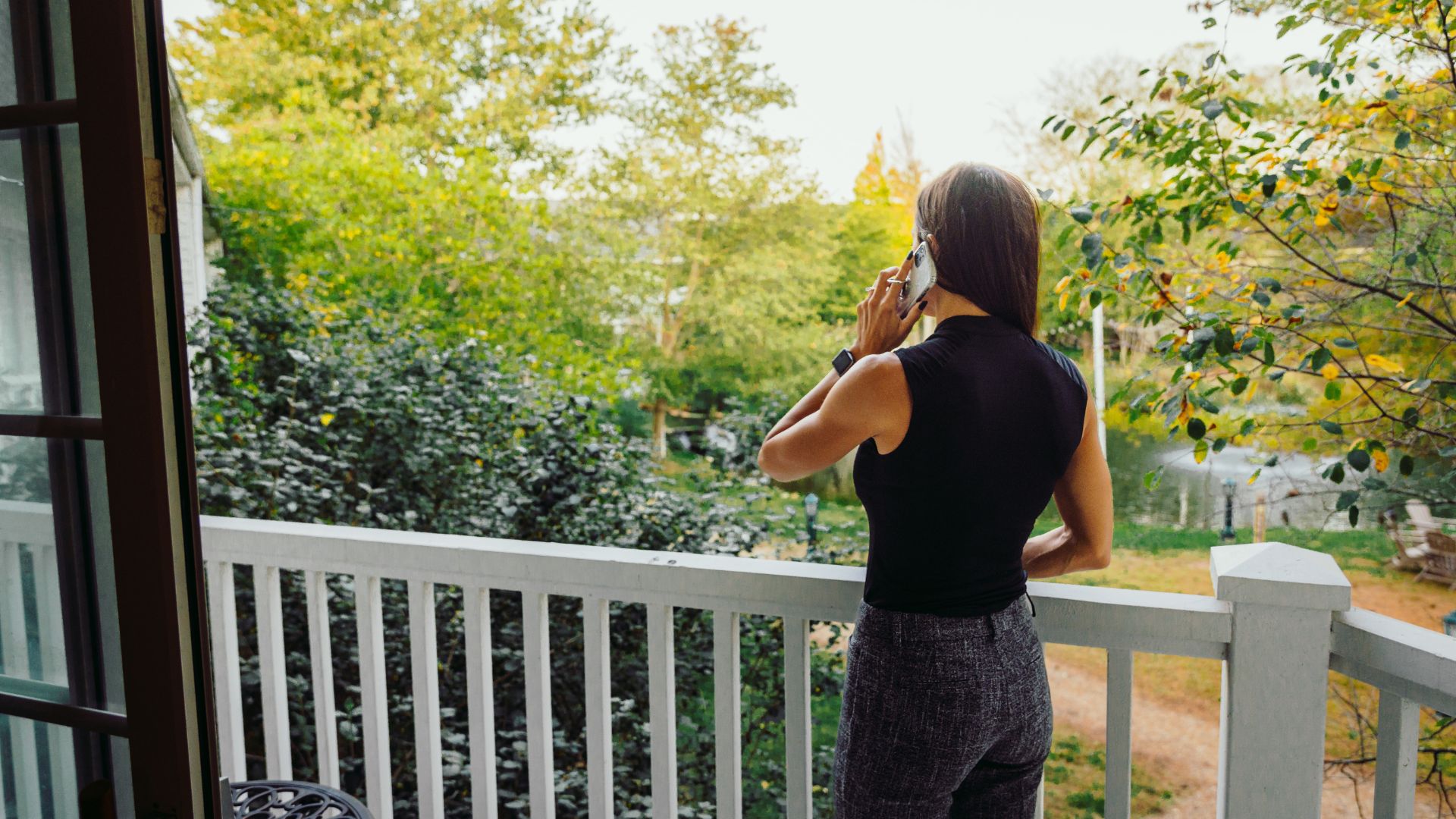 a woman on a porch talking on a cell phone