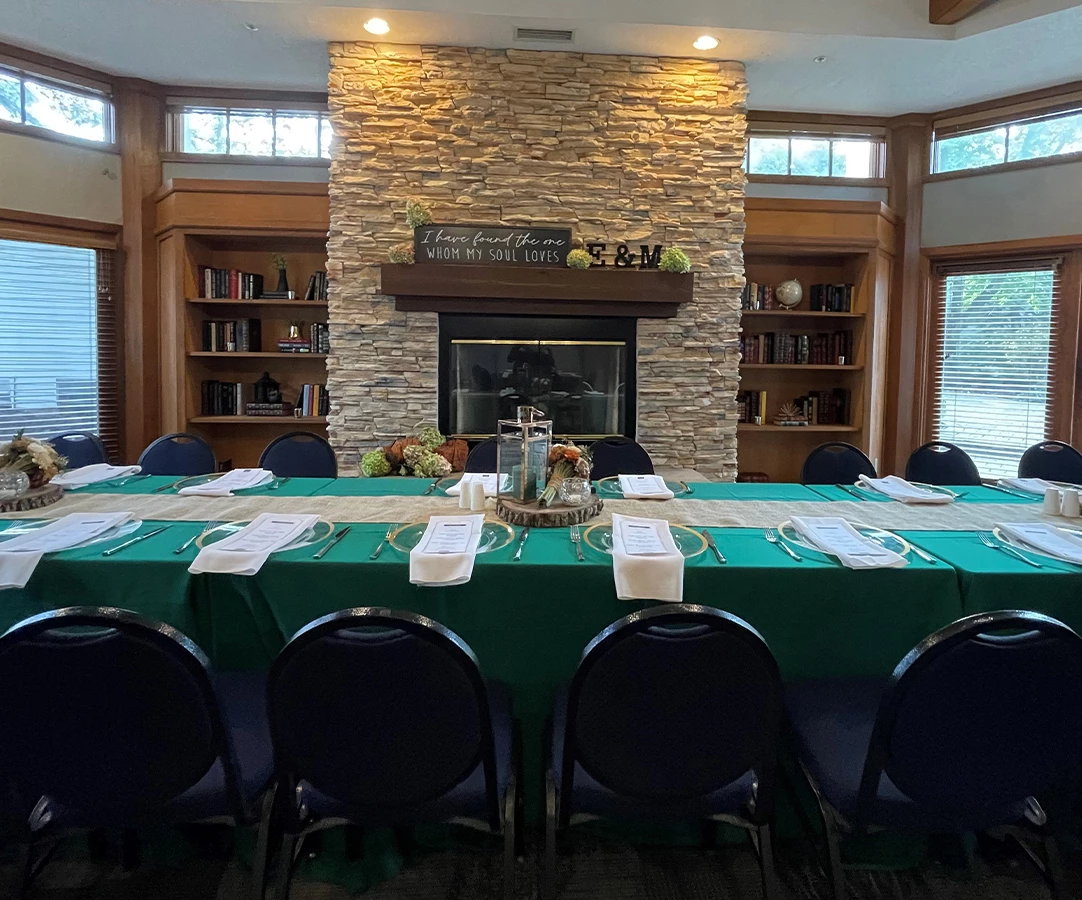 a room with a fireplace and a table with green tablecloths