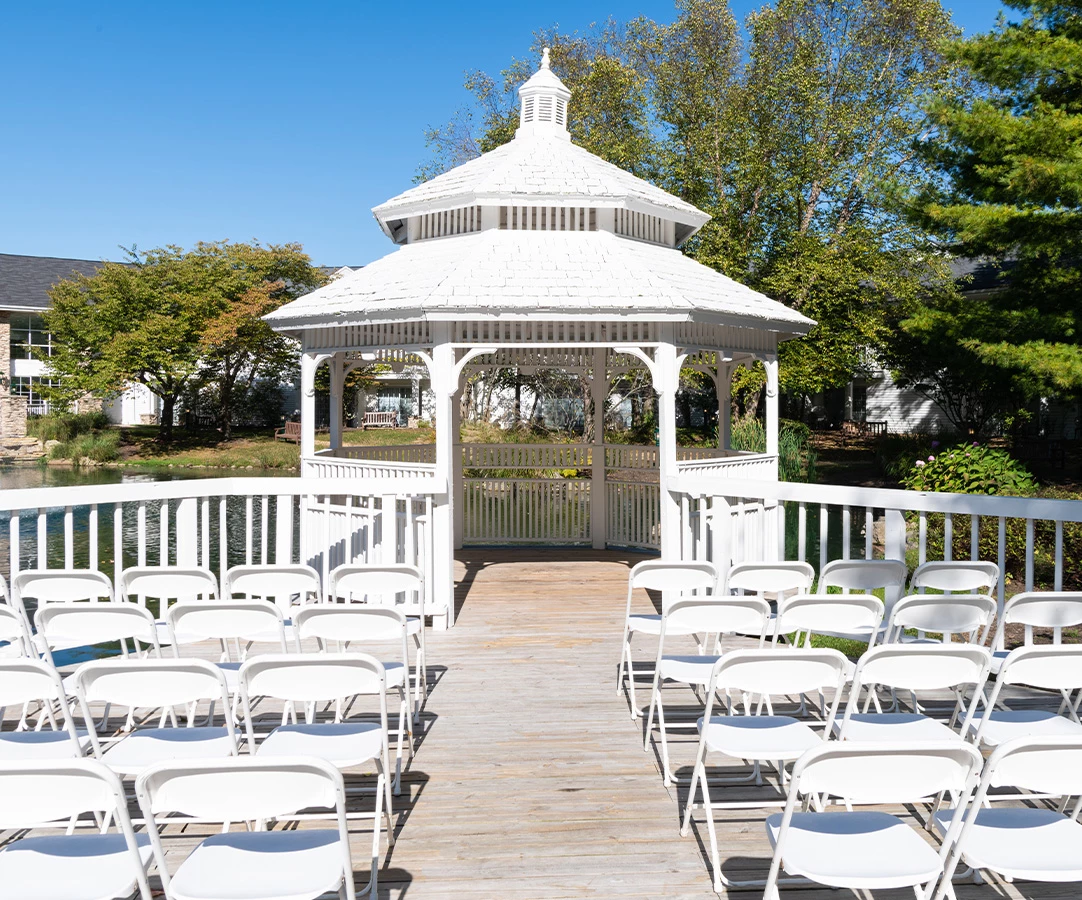 a white gazebo with chairs and a white railing