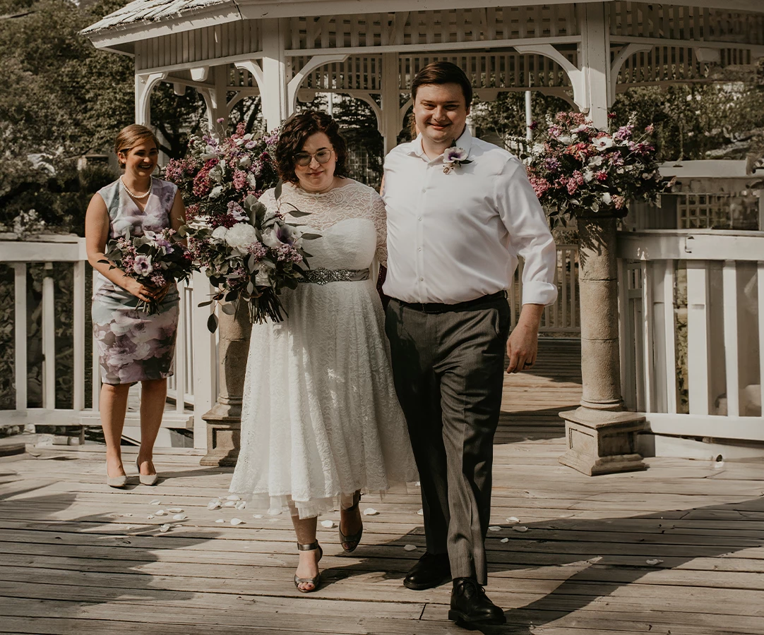 a man and woman walking down a wooden deck with flowers