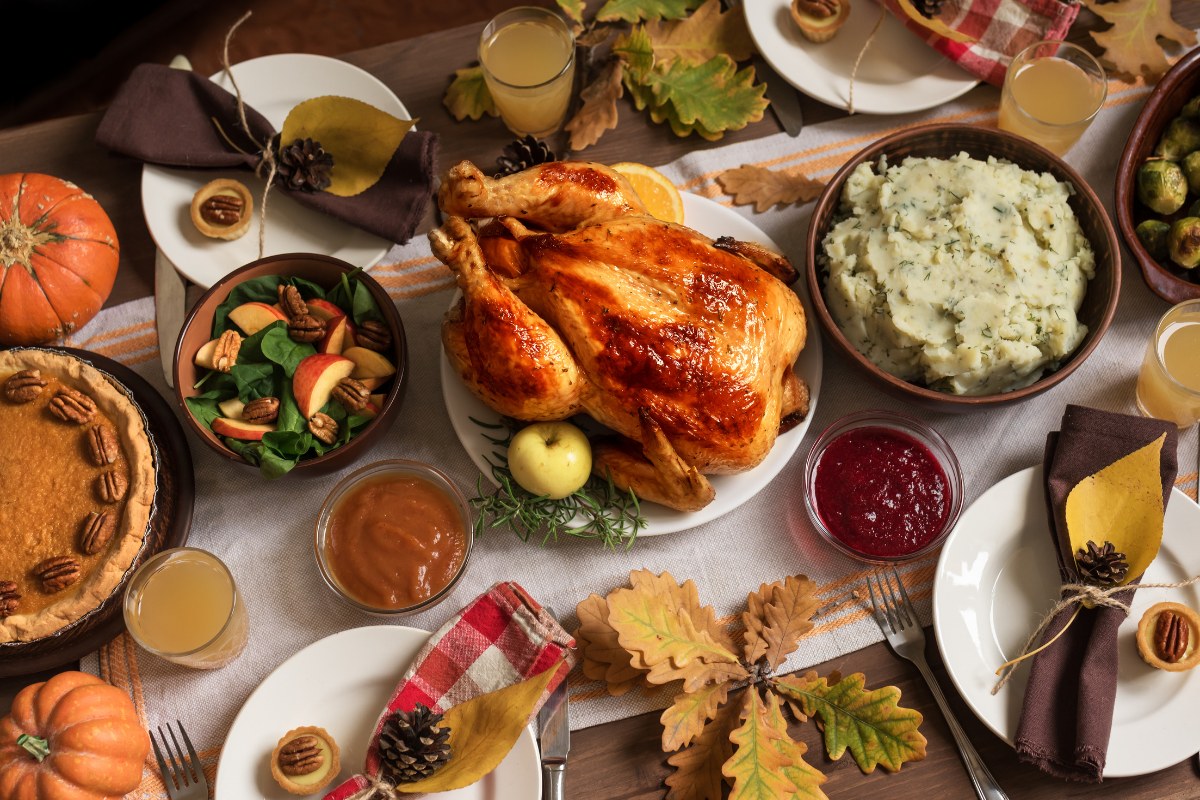 Thanksgiving dinner table with roast turkey, pies and autumn sides