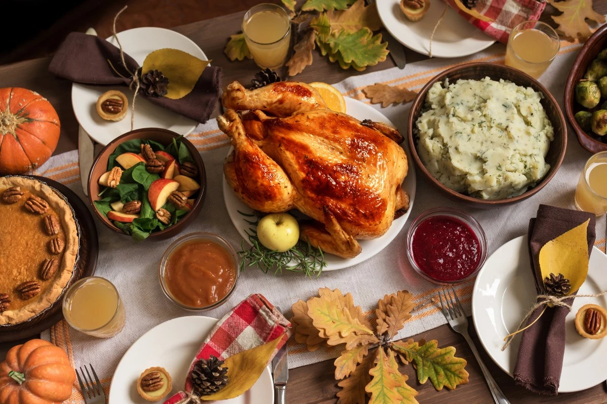 Thanksgiving dinner table with roast turkey, pies and autumn sides