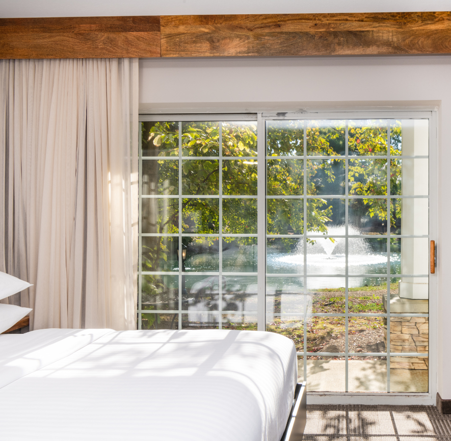a bed with white sheets and a glass door