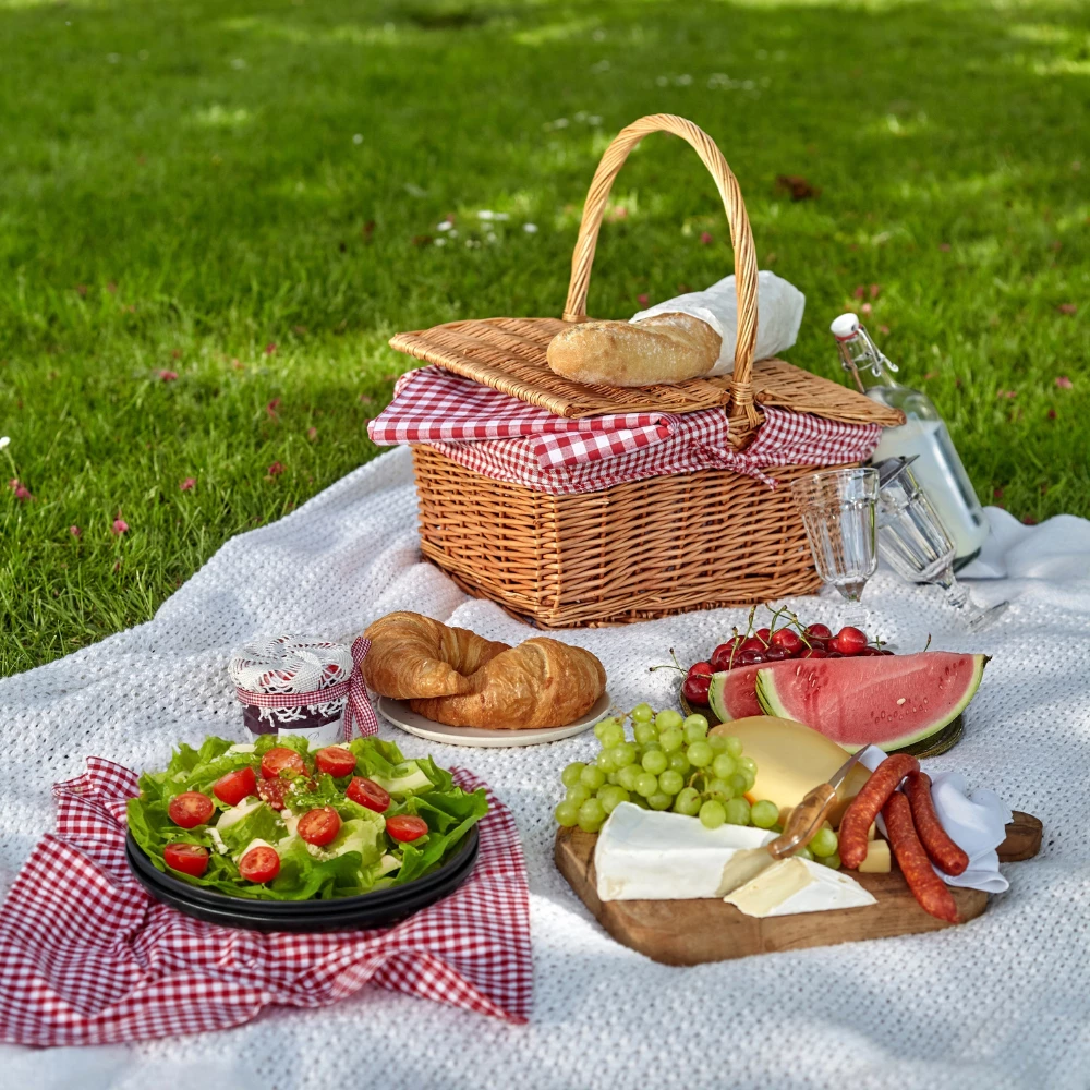 a picnic basket with food on a blanket on grass
