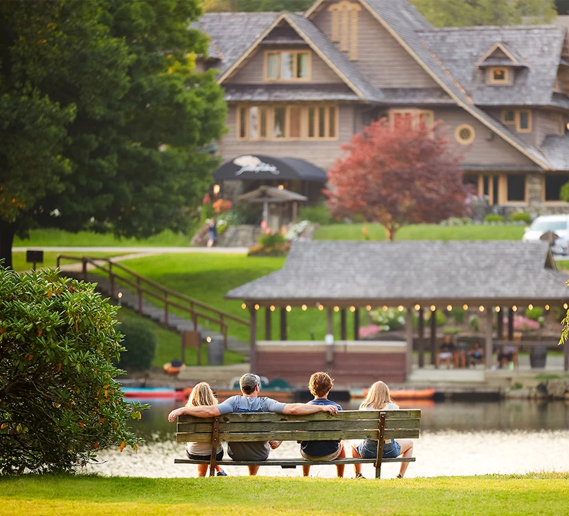 a group of people sitting on a bench by a lake