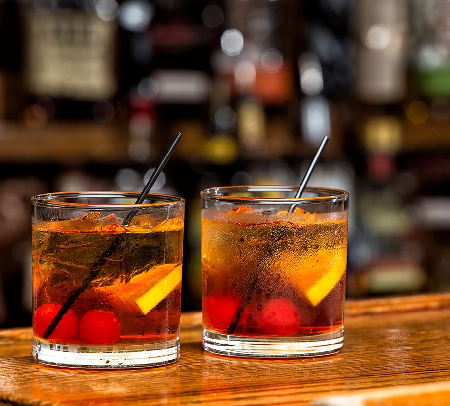 two glasses with liquid and straws on a bar
