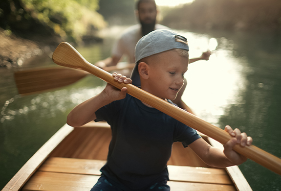 a boy holding a paddle in a boat