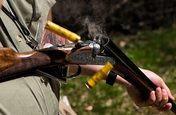 a person holding a shotgun with cartridges in the air