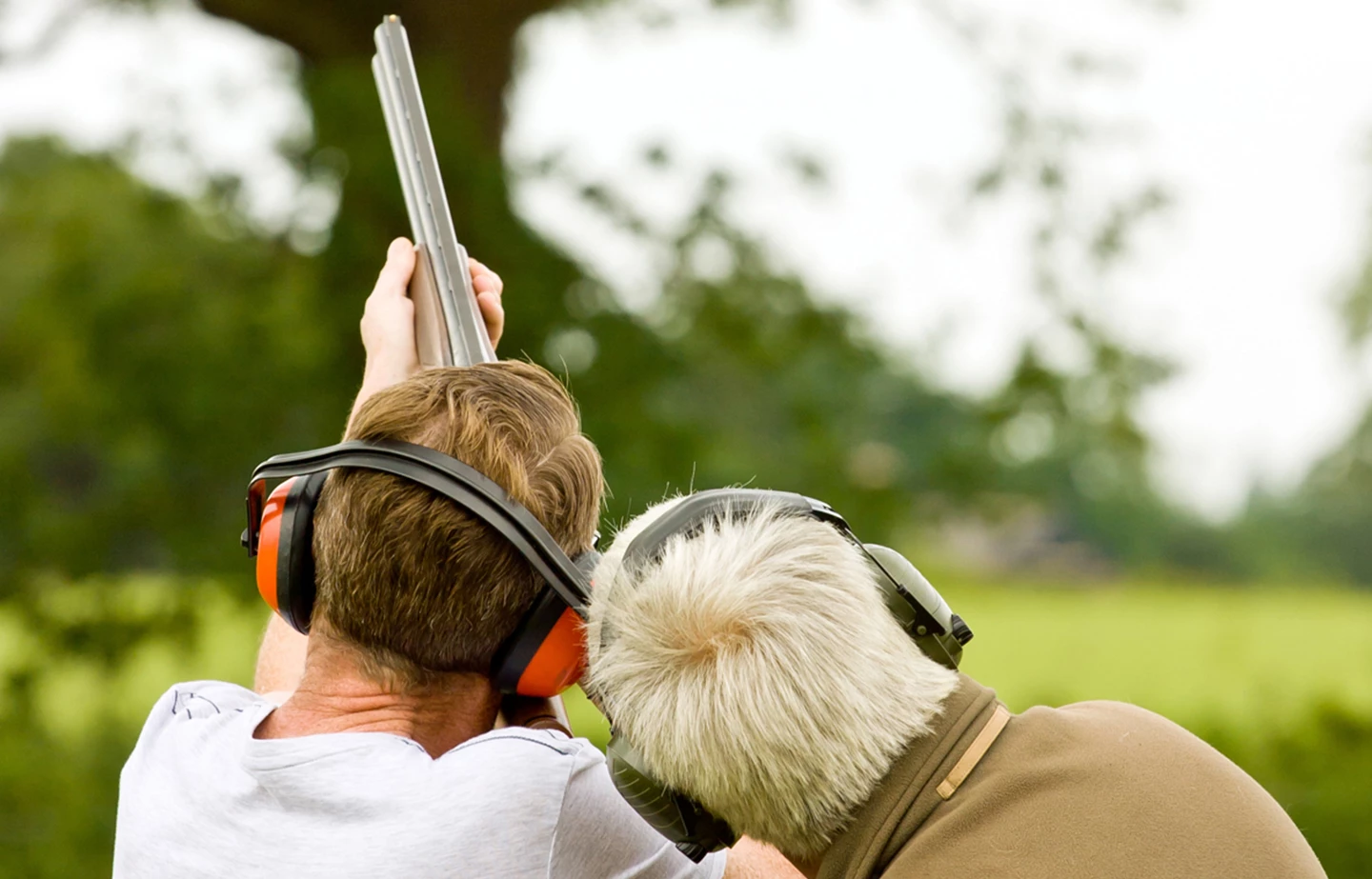a man aiming a gun with another man behind him
