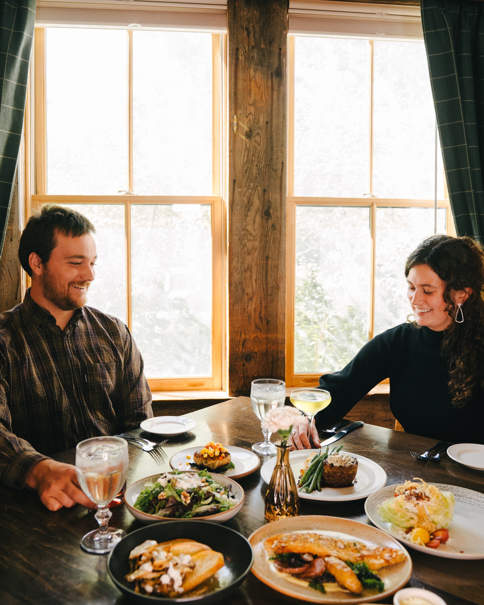 a man and woman sitting at a table with food.