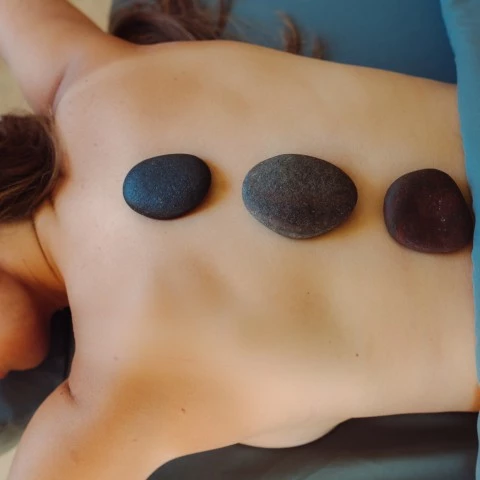 a woman lying down with stones on her back