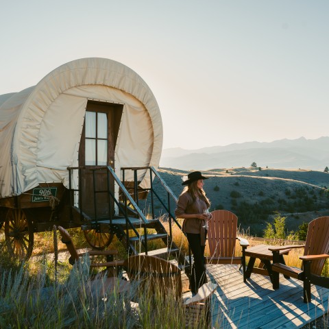 a woman standing on a deck with a wagon and chairs