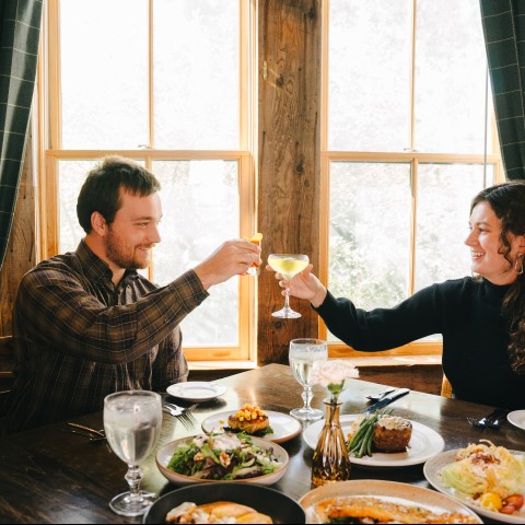 a man and woman sitting at a table with food and drinks