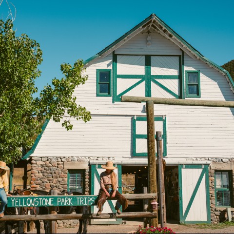 two people sitting on a fence in front of a barn