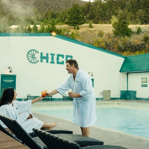a man and woman in white robes by a pool