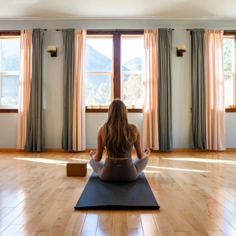 a woman sitting on a mat in front of a window
