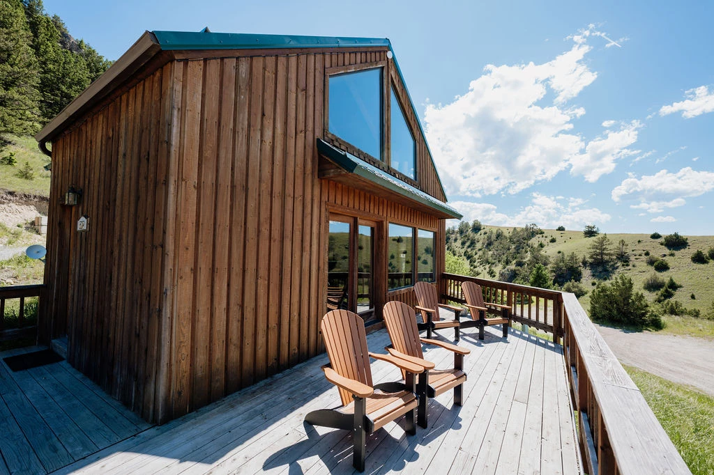 a wooden house with chairs on a deck