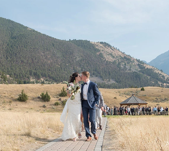 a man and woman kissing on a path with a group of people in the background