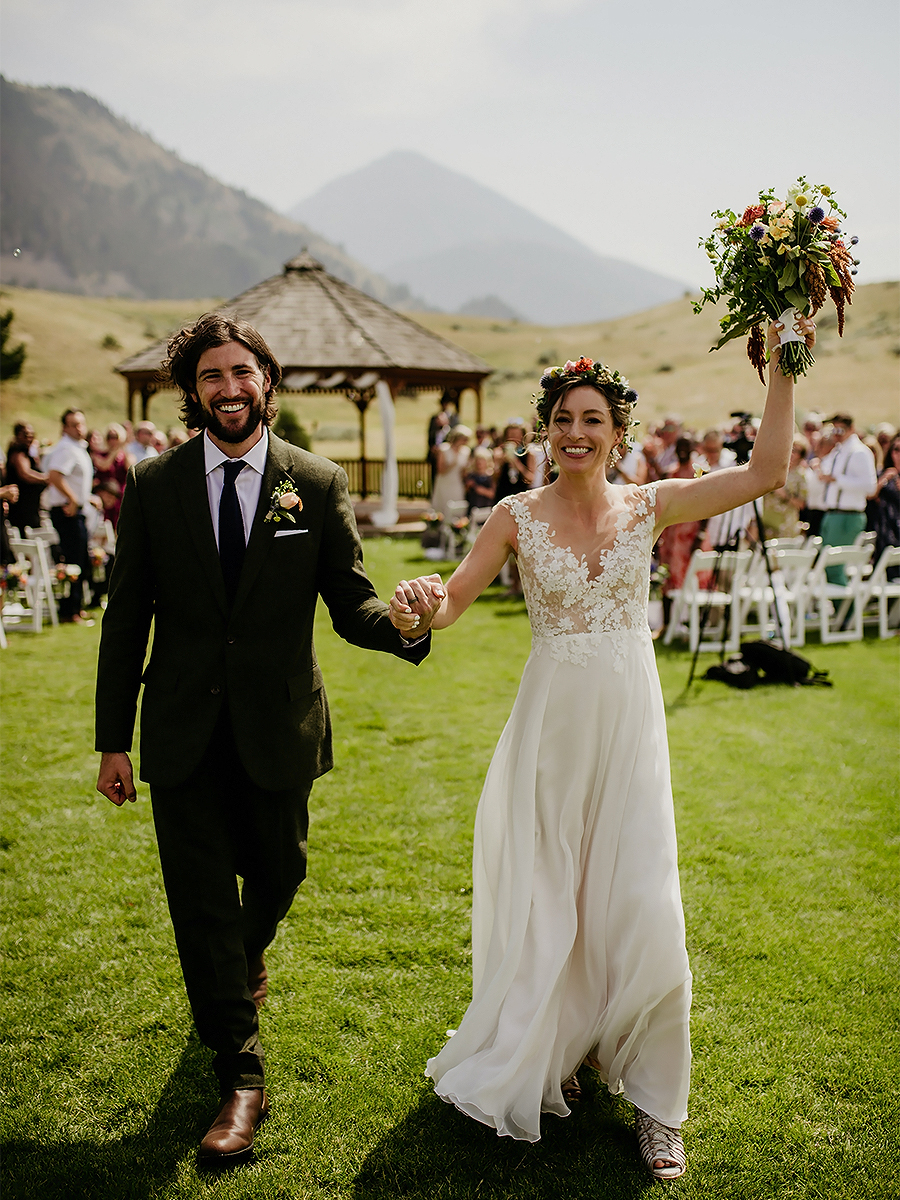a man and woman holding hands and walking down a field
