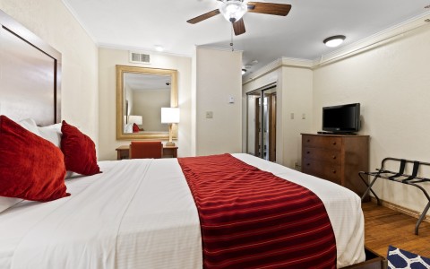 a bed with a red blanket and a ceiling fan