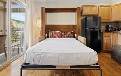 a bed with a black refrigerator in a room